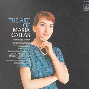 May include: A vinyl record cover titled The Art of Maria Callas featuring a portrait of Maria Callas wearing a blue textured short-sleeved top, a pearl necklace, and a gold bracelet. The black background includes white text listing various operas.