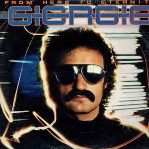 Puede incluir: Un hombre con bigote que lleva gafas de sol y una camisa negra. El fondo es una imagen borrosa de un horizonte urbano con rayas de luz.