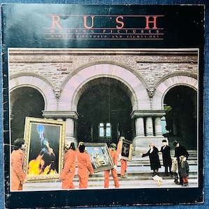 May include: Album cover for Rush's "Moving Pictures" album. The cover features a group of people in orange jumpsuits carrying framed paintings in front of a stone building with arched doorways. The album title and band name are at the top.