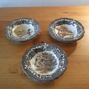 Könnte beinhalten: Drei Keramikschalen mit braunen und schwarzen Blumenmustern und Vogelbildern. Die Schalen stehen auf einer Holzoberfläche.