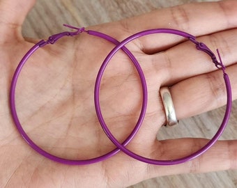 May include: A pair of large purple hoop earrings. The earrings are made of a thin metal and have a simple, classic design.