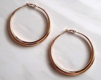 May include: A pair of gold hoop earrings. The earrings are large and have a thick, rounded shape.