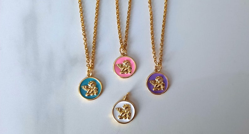 K&ouml;nnte beinhalten: Vier goldene Halsketten mit Engel-Anh&auml;ngern. Die Anh&auml;nger sind rund und haben verschiedene farbige Emaille-Hintergr&uuml;nde: T&uuml;rkis, Rosa, Lila und Wei&szlig;.