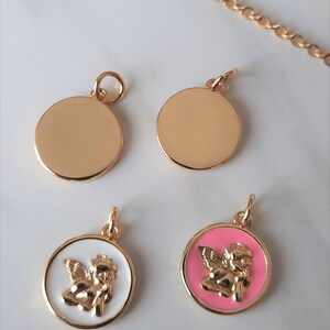 K&ouml;nnte beinhalten: Vier goldfarbene Anh&auml;nger, zwei sind einfache Kreise, einer ist ein wei&szlig;er Kreis mit einem goldenen Cherub, und der andere ist ein rosa Kreis mit einem goldenen Cherub.