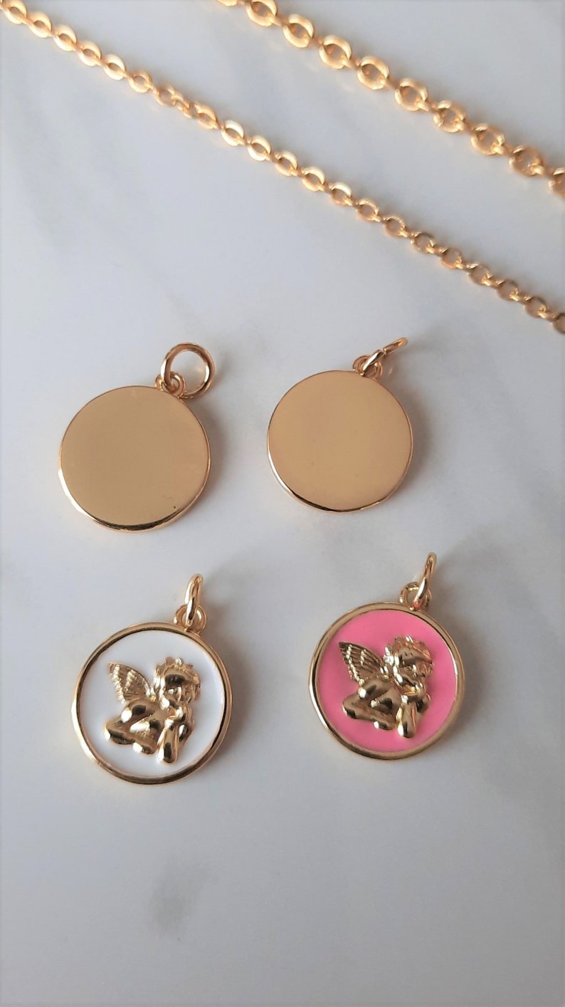 K&ouml;nnte beinhalten: Vier goldfarbene Anh&auml;nger, zwei sind einfache Kreise, einer ist ein wei&szlig;er Kreis mit einem goldenen Cherub, und der andere ist ein rosa Kreis mit einem goldenen Cherub.