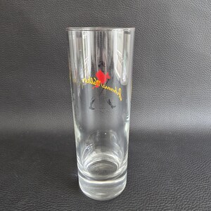 May include: A clear, tall glass with a slightly flared rim. The glass features a red and yellow logo with the text "Johnnie Walker" in a cursive font. The logo includes a silhouette of a man with a top hat.
