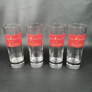 May include: Four clear glass shot glasses with a red label that says "Keep Walking Johnnie Walker".