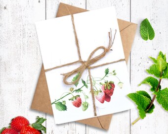 May include: A white card featuring a strawberry and leaf watercolour illustration, tied with twine, sits on a brown envelope. Fresh strawberries and mint sprigs are arranged nearby, creating a fresh, natural aesthetic.