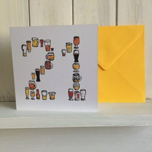 May include: A white card with a yellow envelope. The card features a design of 21 beer glasses and mugs in various shapes and sizes. The number 21 is formed by the glasses and mugs.