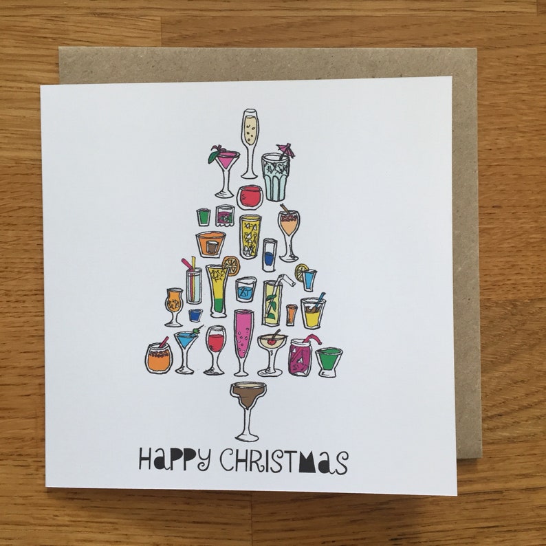 May include: A square greeting card with a white background featuring a colorful illustration of various cocktail glasses arranged in the shape of a Christmas tree. The text at the bottom reads Happy Christmas in black, stylized, sans-serif lettering.