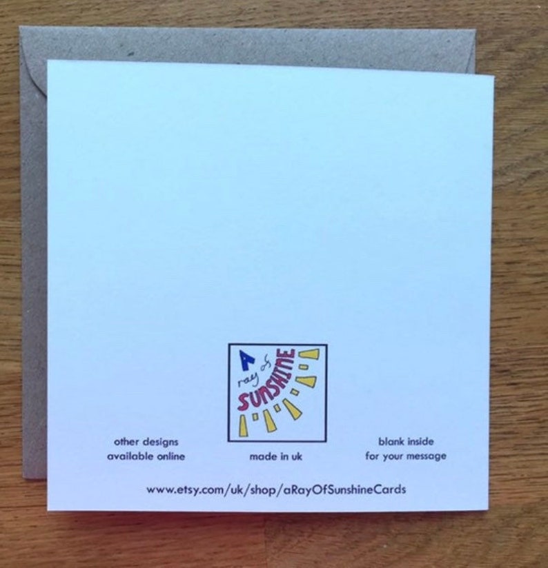 May include: A white card with a colorful sun graphic and the text "a ray of sunshine" in red and blue. The card has the text "other designs available online" and "made in uk" on the bottom left and "blank inside for your message" on the bottom right. The text "www.etsy.com/uk/shop/aRayOfSunshineCards" is printed on the bottom center.