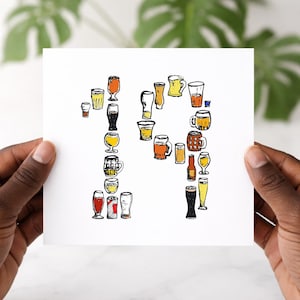 May include: A white card held by hands, featuring a hand-drawn illustration of the number "14" made up of various beer glasses and mugs. The glasses are filled with different types of beer, in shades of amber, gold, and dark brown.