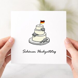 以下が含まれることがあります： 手描きの3段重ねのクリーム色のウェディングケーキのイラストが描かれた正方形の白いグリーティングカード。ケーキには小さな花とドイツの国旗が飾られています。下部には黒い筆記体で「Schönen Hochzeitstag」と印刷されています。