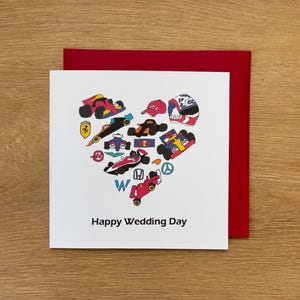 Könnte beinhalten: Weiße Grußkarte mit rotem Umschlag. Das Design zeigt ein herzförmiges Arrangement aus bunten Rennwagen, Helmen und Kappen. Der Text "Happy Wedding Day" ist unten auf der Karte aufgedruckt.