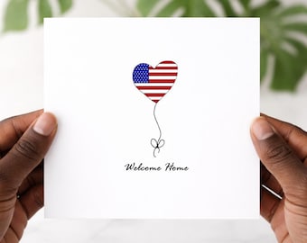 May include: A square white greeting card featuring a heart-shaped balloon with the red, white, and blue American flag pattern. A thin black line extends from the heart to a small bow at the bottom. The text Welcome Home is printed in black.