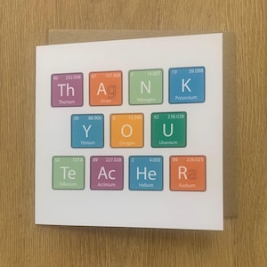 May include: A white card with the words "Thank You" spelled out using periodic table elements. The card is on a brown envelope. The words are in colourful squares.