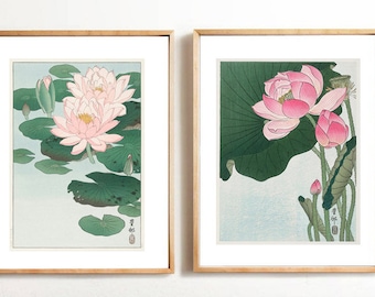 May include: Two framed prints of Japanese woodblock prints featuring pink lotus flowers. The prints are on a white background and have a light blue sky in the background.