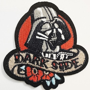 May include: Embroidered patch featuring Darth Vader's helmet within a red oval, with the words "DARK SIDE" and "BOY" in a banner. The patch includes red and blue floral accents, all outlined in black.