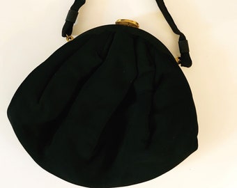 May include: A black fabric evening bag with a rounded shape and a gold clasp. The bag has a single strap.