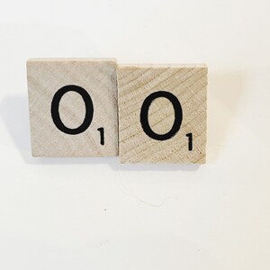 Puede incluir: Dos fichas de letras de madera con la letra "O" en cada ficha. Cada ficha tiene el número "1" impreso.