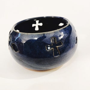 Op de afbeelding: Een donkerblauwe keramische kom met een kruisvormig uitsnijdingontwerp. De kom heeft een gladde, geglazuurde afwerking en een afgeronde vorm.