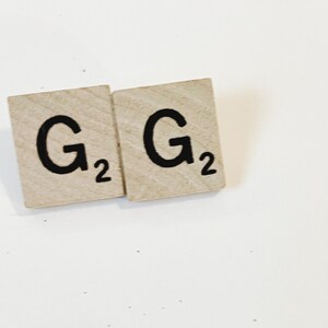 May include: Two wooden letter tiles with the letter "G" and the number "2" on each tile.
