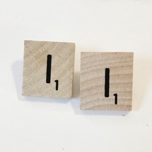 Puede incluir: Dos fichas de madera con la letra "I" y el número "1" impresos en ellas.