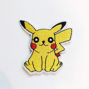 May include: Yellow embroidered patch of a cartoon Pikachu sitting with its arms crossed and a smile on its face.