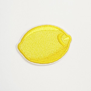 Może przedstawiać: Haftowana żółta naszywka z cytryną z białym obramowaniem. Cytryna ma teksturowany wygląd i mały szczegół segmentu. Nadaje się do odzieży, toreb lub innych przedmiotów z tkaniny.