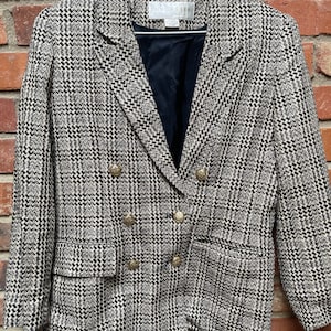 Può includere: Un blazer in tweed nero e bianco con bottoni dorati. Il blazer ha una chiusura a doppio petto e due tasche a lembo. L'etichetta recita "Doncaster".