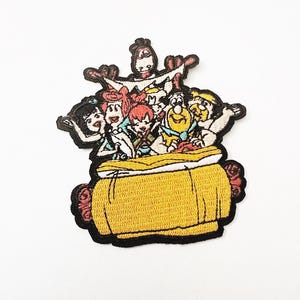 Może przedstawiać: Haftowana naszywka przedstawiająca grupę postaci z kreskówek w żółtej beczce. Naszywka ma czarną obwódkę i przedstawia kilka postaci o różnych odcieniach skóry, kolorach włosów i ubraniach. Beczka jest żółta z czerwonymi akcentami.