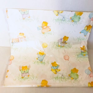 May include: White wrapping paper with a repeating pattern of teddy bears wearing different colored clothing and holding balloons. The bears are playing on a seesaw and holding presents.