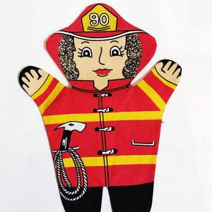 Puede incluir: Marioneta de bombero roja y amarilla con una cuerda negra y un pico. La marioneta tiene una cara sonriente con cabello negro y un sombrero rojo con el número 90.