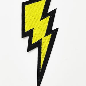 May include: Embroidered yellow lightning bolt patch with a black border. The patch is a vibrant yellow color and has a textured appearance. This patch can be used to decorate clothing, bags, or other fabric items.
