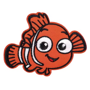 Puede incluir: Parche bordado con un pez payaso de dibujos animados en naranja, negro y blanco. El pez tiene ojos grandes y expresivos y una boca sonriente. El parche está diseñado con un contorno detallado y un aspecto texturizado.