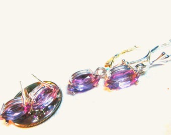 May include: A pair of silver earrings and a matching stud earring with oval-cut, purple gemstones. The earrings have a lever-back closure. The gemstones have a gradient of purple and pink hues.