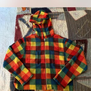 May include: A hooded jacket with a vibrant plaid pattern in red, yellow, green, and blue. The jacket has a full zipper, two front pockets, and a cozy, textured appearance. The colorful design makes it a standout piece.