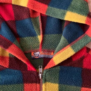May include: A colorful, hooded fleece jacket with a plaid pattern in shades of red, orange, yellow, green, and blue. The jacket has a full zipper and a Bulldog brand label. The fleece material appears soft and warm.