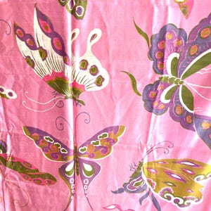 May include: A pink fabric featuring a repeating pattern of butterflies in shades of purple, olive green, and white. The butterflies are depicted with detailed wing markings and long antennae, distributed across the surface of the textile.