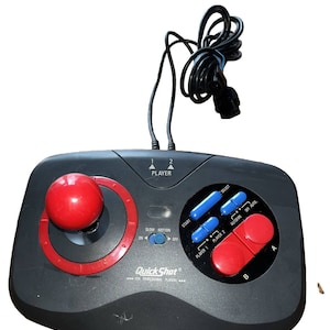 May include: A black Quick Shot joystick with a red ball top, two red buttons, and blue buttons labelled "Start", "Select", "Player 1", "Player 2", "Autofire", and "Off Auto".