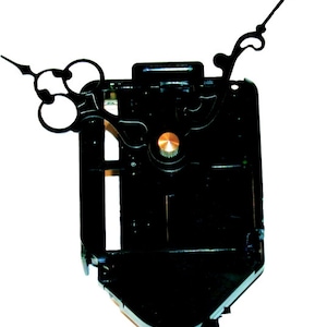May include: Black clock movement with a gold knob and black hands. The hands are designed with a decorative flourish.