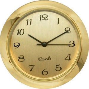 May include: Gold-toned clock face with black hour and minute hands and black Arabic numerals. The clock face reads "Quartz".