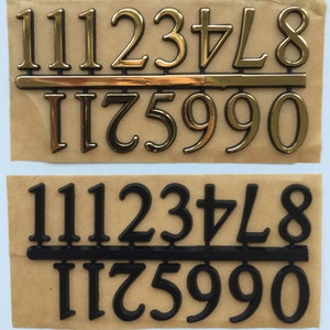 May include: Two sets of adhesive numbers in gold and black. The gold set includes numbers 1, 2, 3, 4, 7, 8, 5, 9, and 0. The black set includes the same numbers. Each set is arranged on a brown backing.