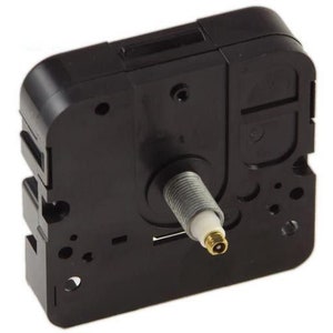 May include: Black clock movement with a silver winding stem and a gold-colored tip. The movement has a black plastic casing with a rectangular shape.