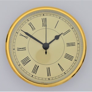 May include: A gold-rimmed clock face with black Roman numeral hour markers and black hands. The clock face is cream-colored and has a subtle texture.