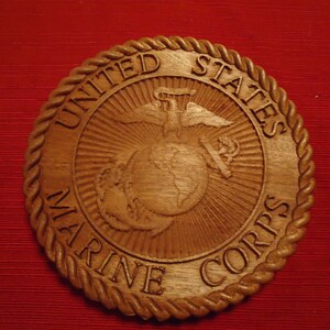 May include: A wooden plaque with a rope border and the words "United States Marine Corps" surrounding the Marine Corps emblem.
