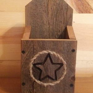 May include: A rustic wooden wall mounted box with a star design carved into the front. The box is made of reclaimed wood and has a natural finish.