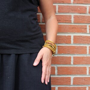 May include: A person wearing a black top and skirt with multiple yellow and orange beaded bracelets on their wrist.