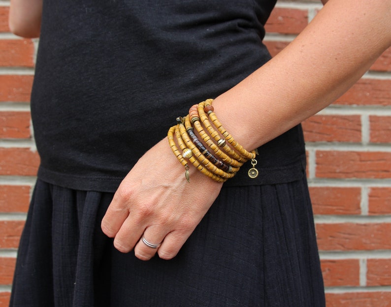 May include: A stack of yellow, brown, and gold beaded bracelets with small charms on the ends.