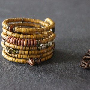 May include: A multi-layered bracelet made of yellow, brown, and white beads. The bracelet is wrapped around itself several times, creating a thick, textured look.